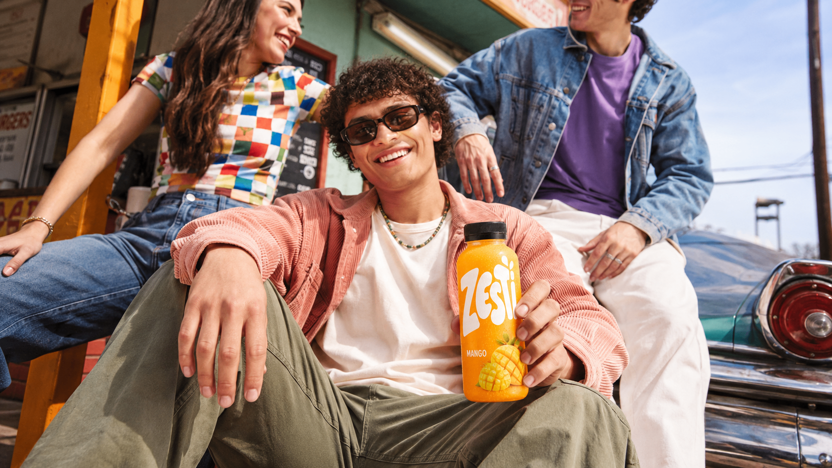 Youthful lifestyle direction for the Mango variant — casual styling, bright daylight and product-forward framing.